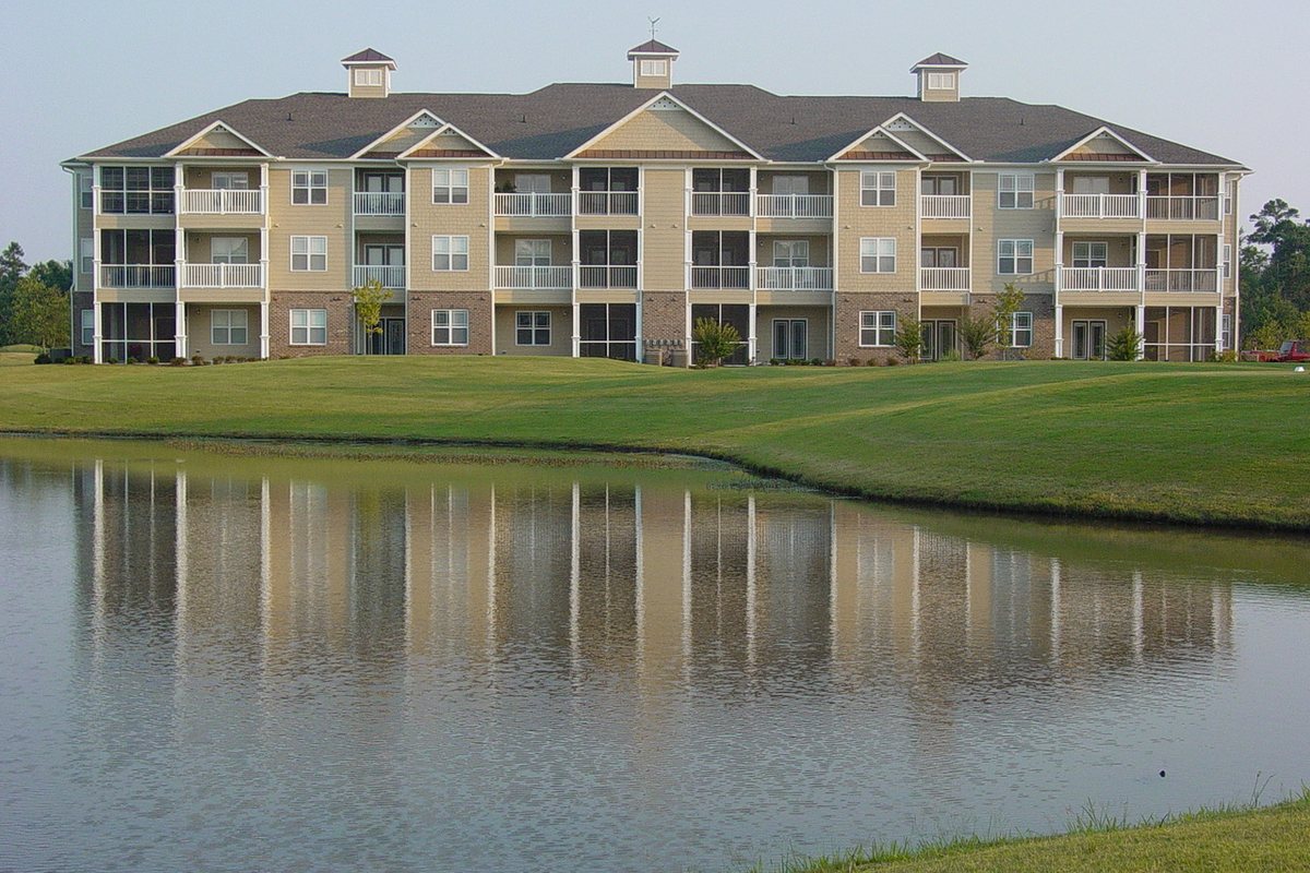 Three-story apartment building overlooking a pond, built by members of the FEMCO team
